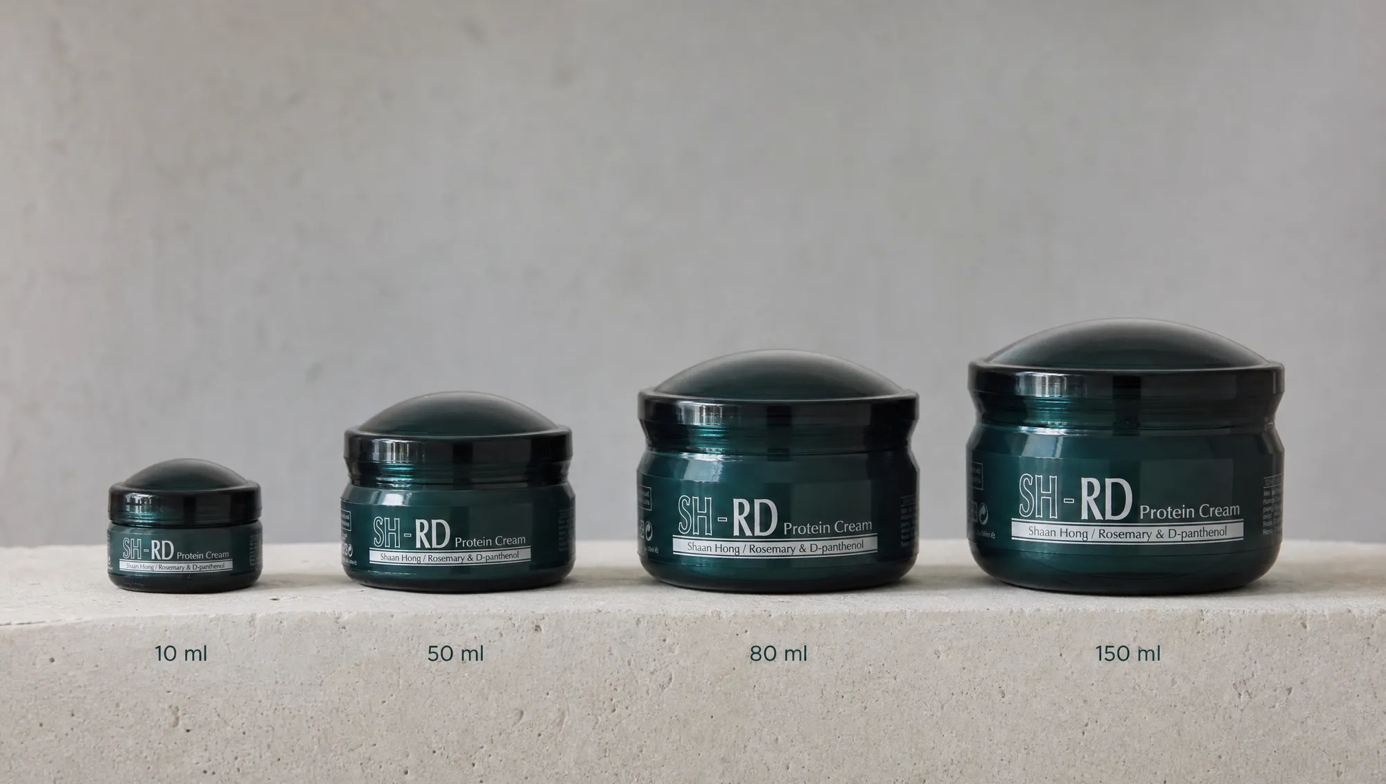 Four sizes of SH-RD Protein Cream lined up from the 10 ml travel pot to the 150 ml jar